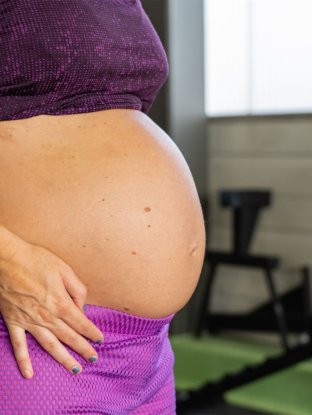 Pregnant woman with her hand on her belly in the training hall